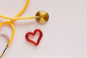 plastic stethoscope with coil heart on pink background