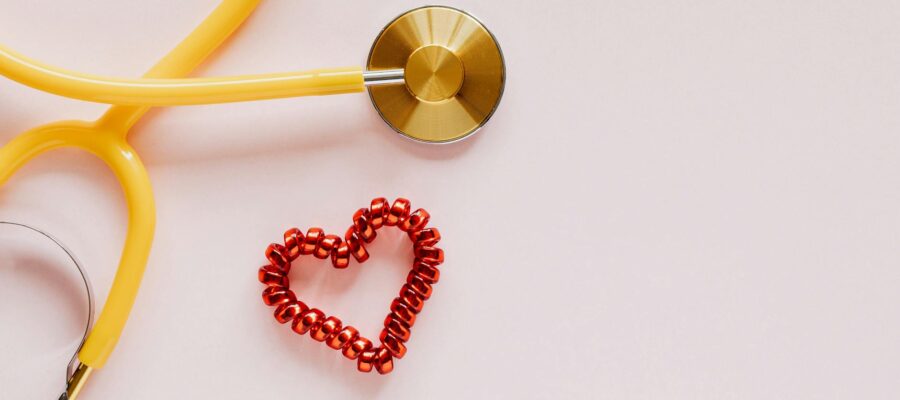 plastic stethoscope with coil heart on pink background