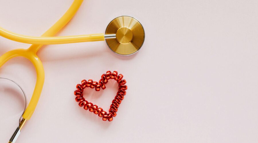 plastic stethoscope with coil heart on pink background