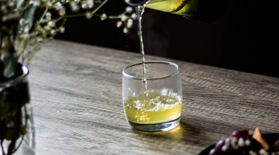 photo of a person pouring green tea into a drinking glass