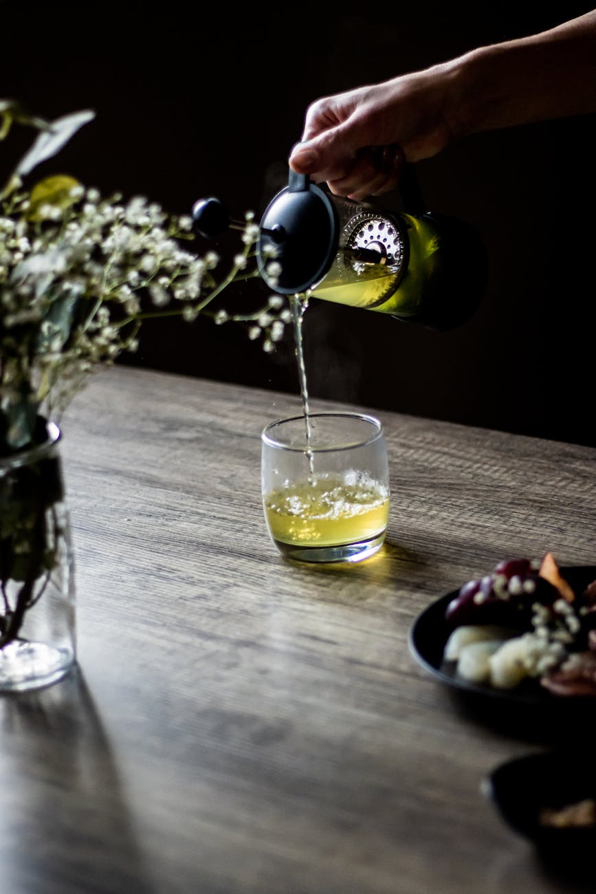 photo of a person pouring green tea into a drinking glass