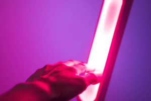 A glowing red light therapy lamp illuminates a person's hand, highlighting the warm red glow against a softly blurred background, symbolizing wellness and rejuvenation.