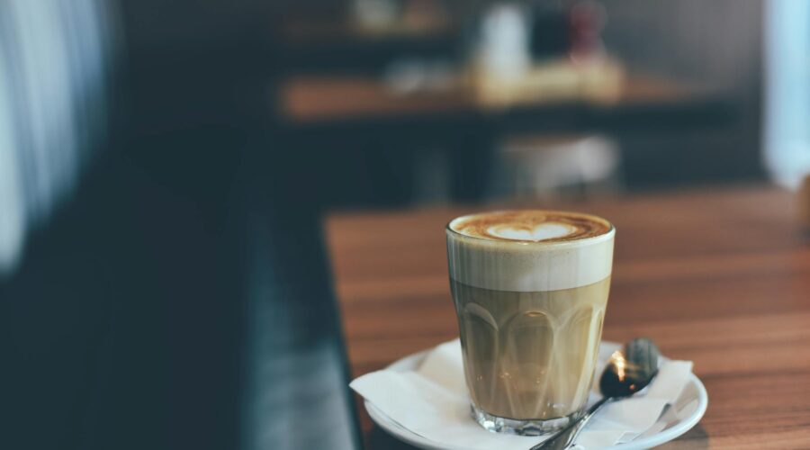 clear drinking glass with brown beverage in white saucer in tilt shift photography